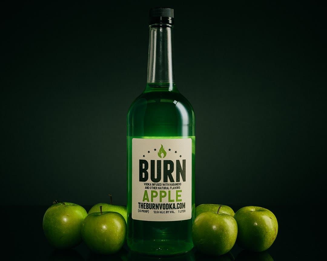 Apple BURN bottle surrounded by green apples